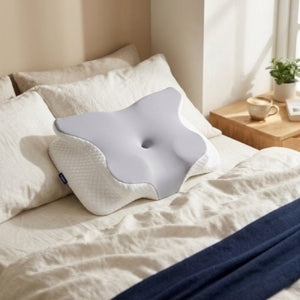 Oreiller cervical papillon Hypna sur un lit aux draps blancs